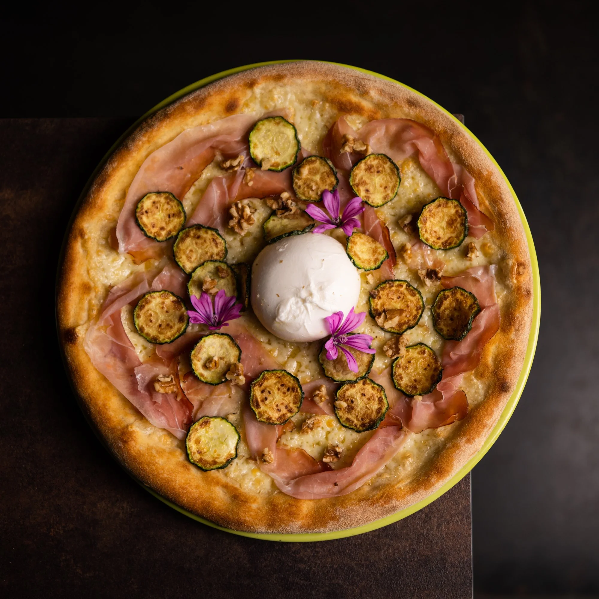 Pizza con zucchine, crudo, noci, burrata al centro e fiori di malva